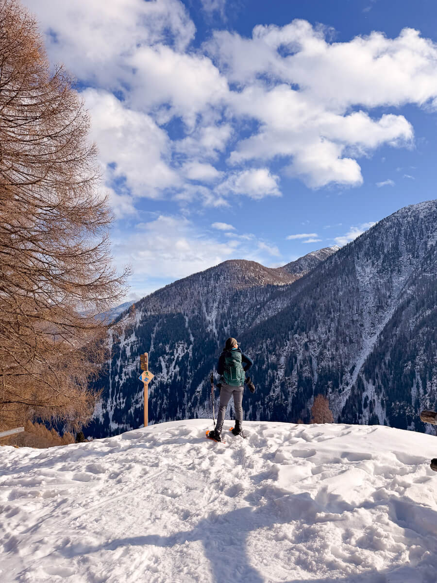 Women snowshoeing on a snowy mountain trail in the Dolomites under a blue sky