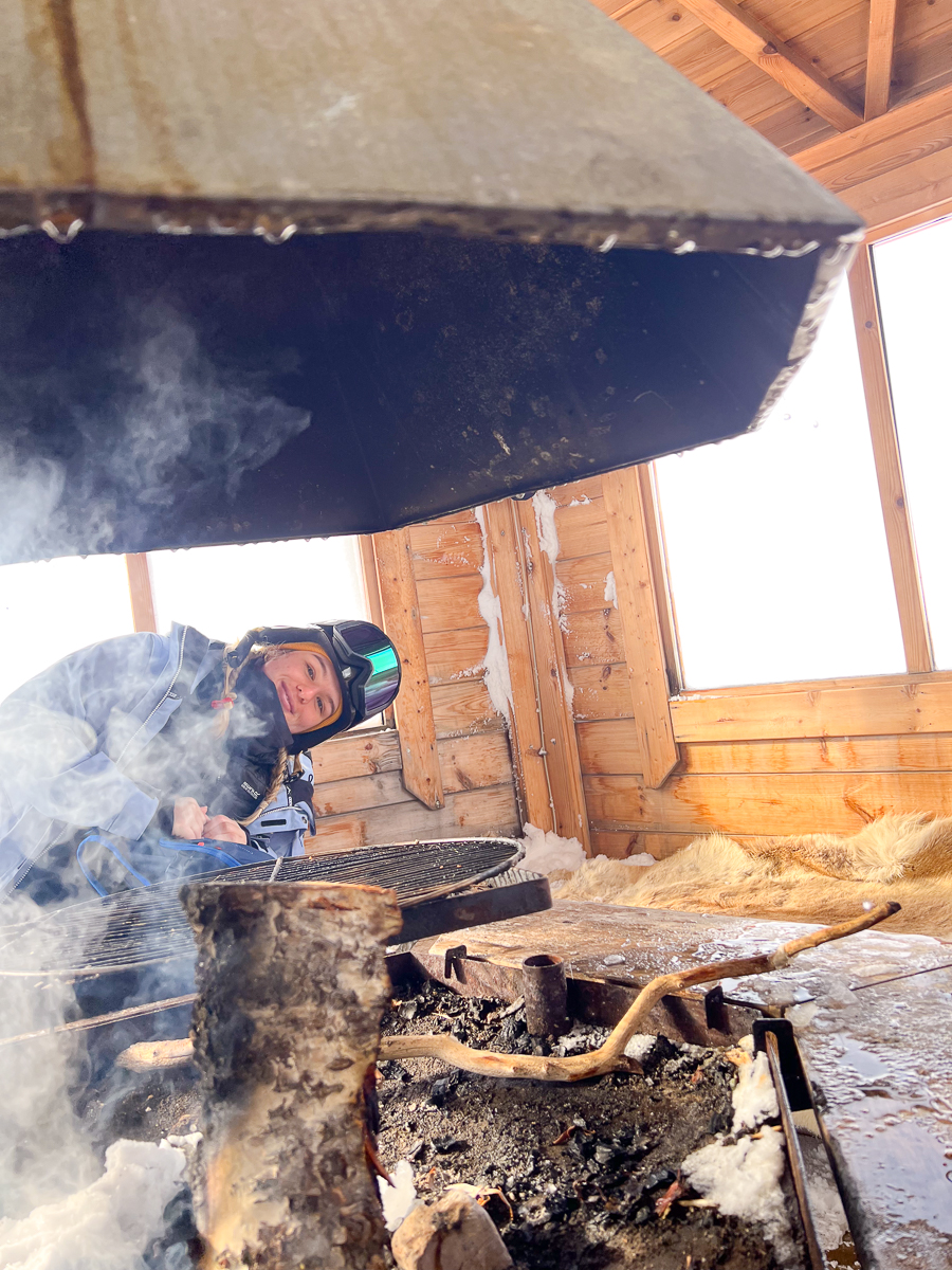 Woman wearing a helmet using a grinder with sparks in a wooden workshop interior