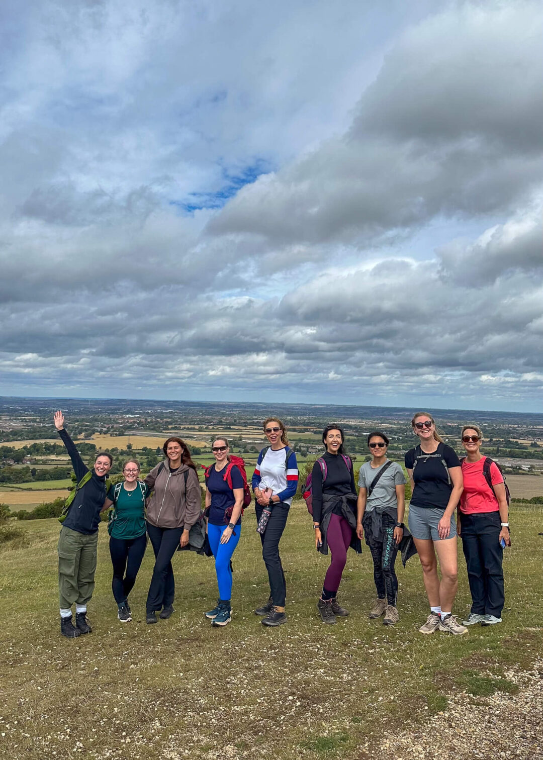 Women hiking on a guided countryside hike, standing on a viewpoint under cloudy skies