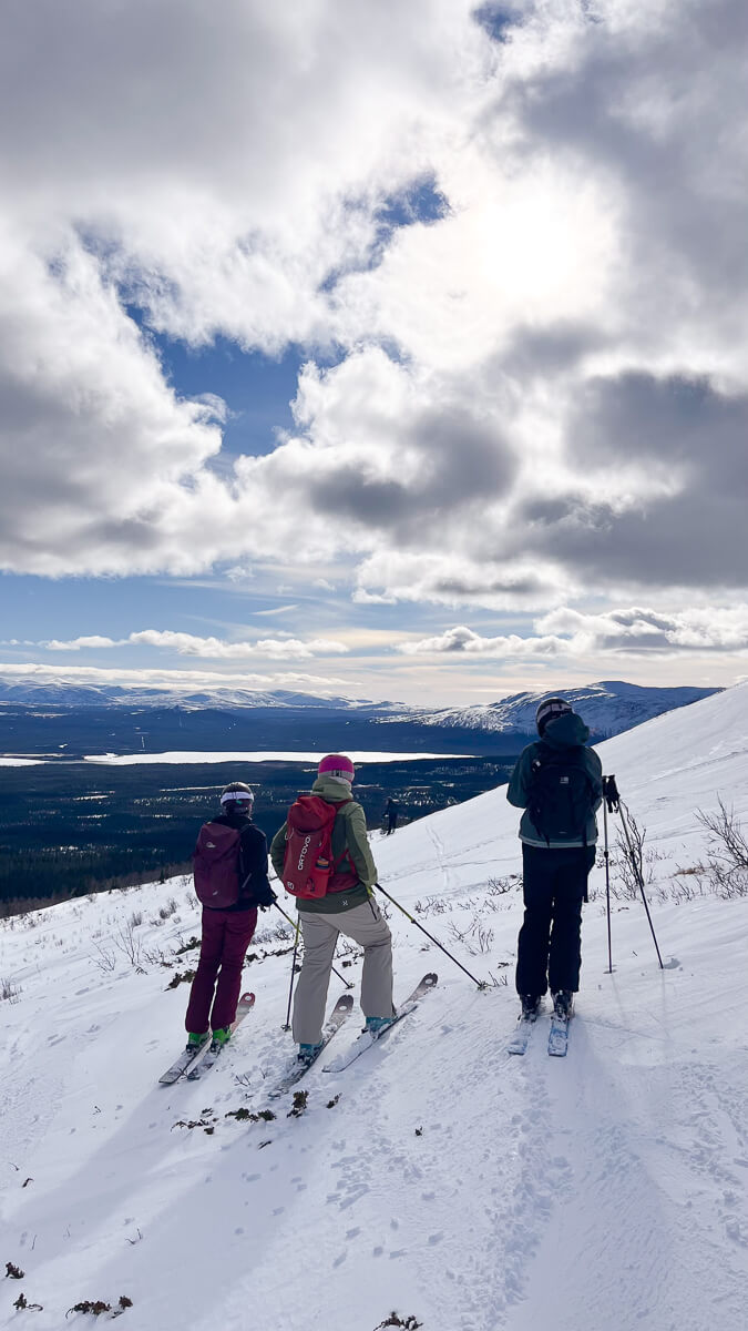 Women skiing on a snowy mountain slope, overlooking a valley under cloudy skies in winter Europe