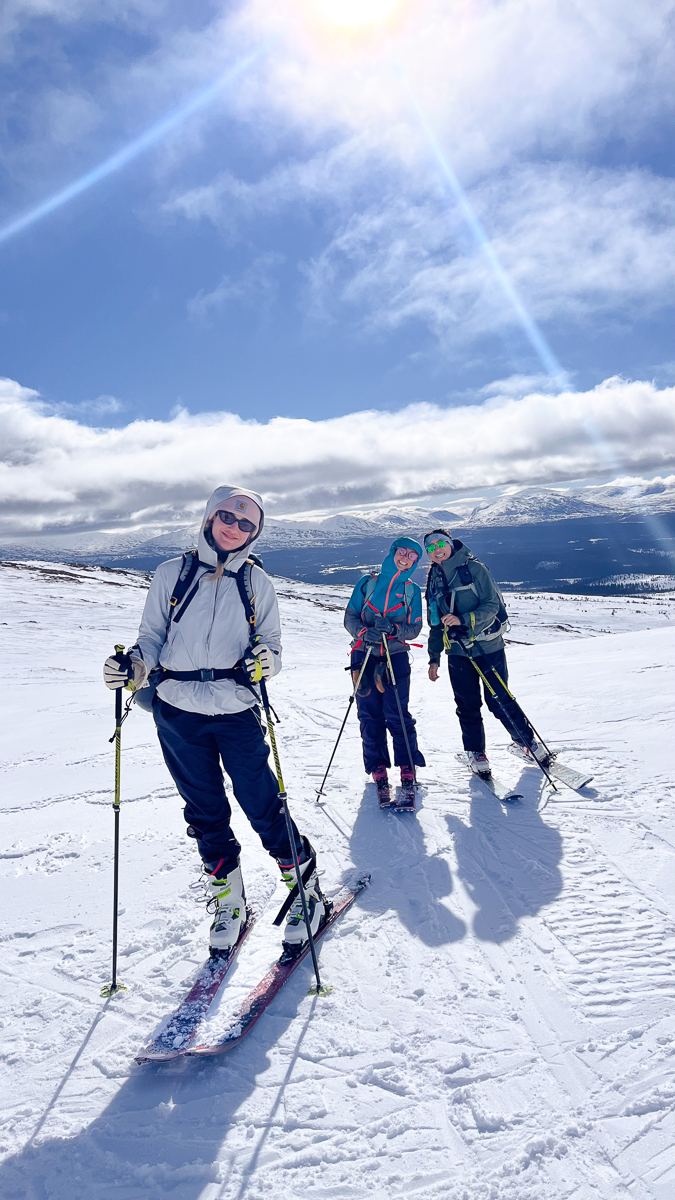 Women ski touring on snowy mountains with skis and poles under cloudy winter skies