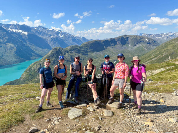 Women hikers on a mountain ridge overlooking an alpine valley and turquoise lake