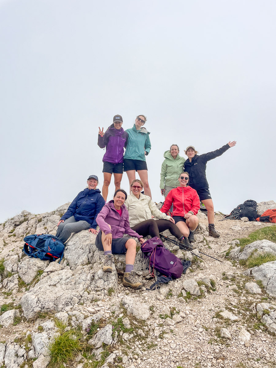 Women hikers pose on a rocky mountain summit during an adventure holiday outdoors