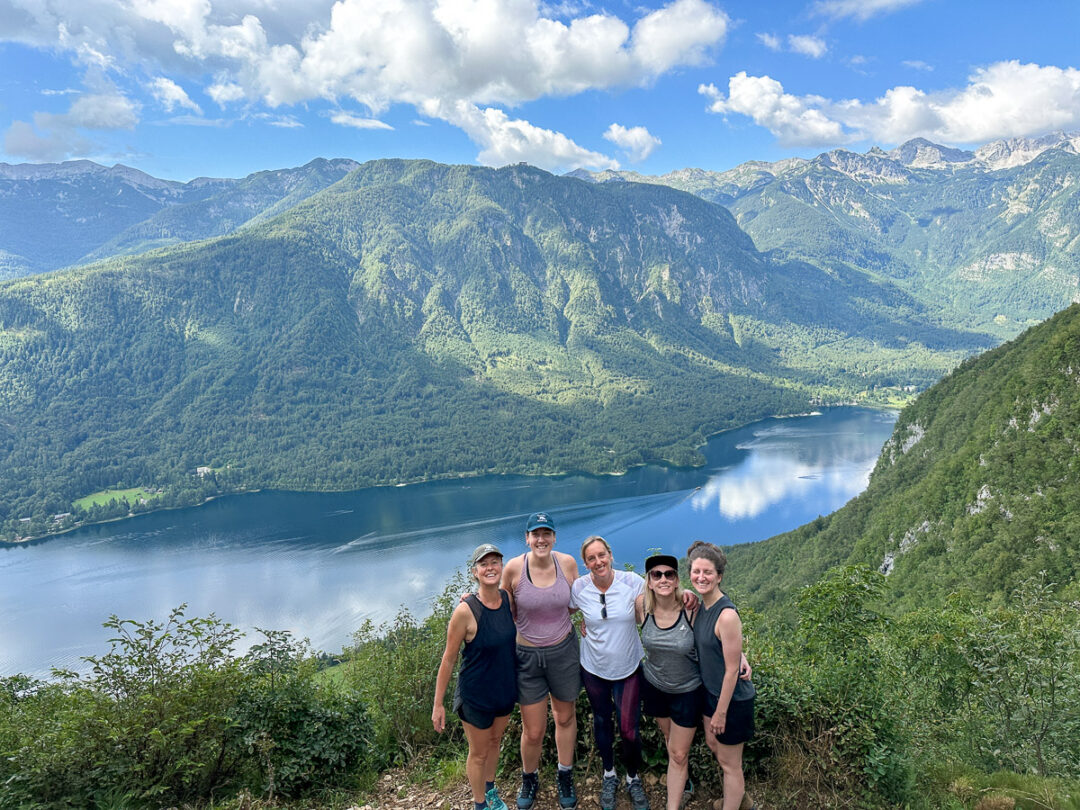 Women hikers overlooking a mountain lake and alpine valley in Europe from a scenic trail viewpoint