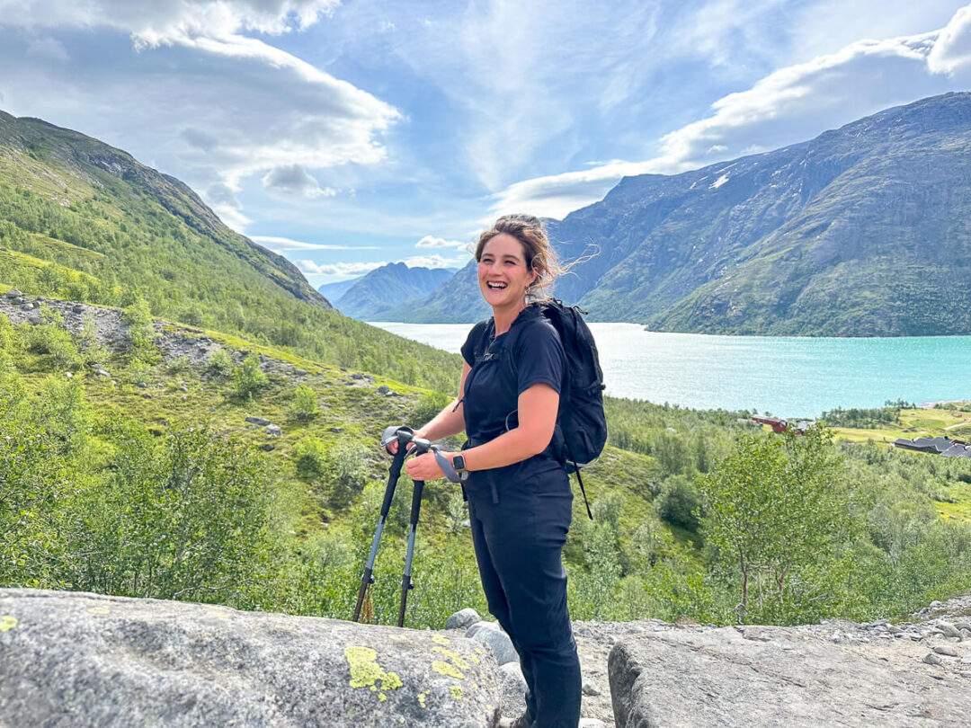 Woman trekking with hiking poles in the mountains overlooking a lake in Europe under a blue sky