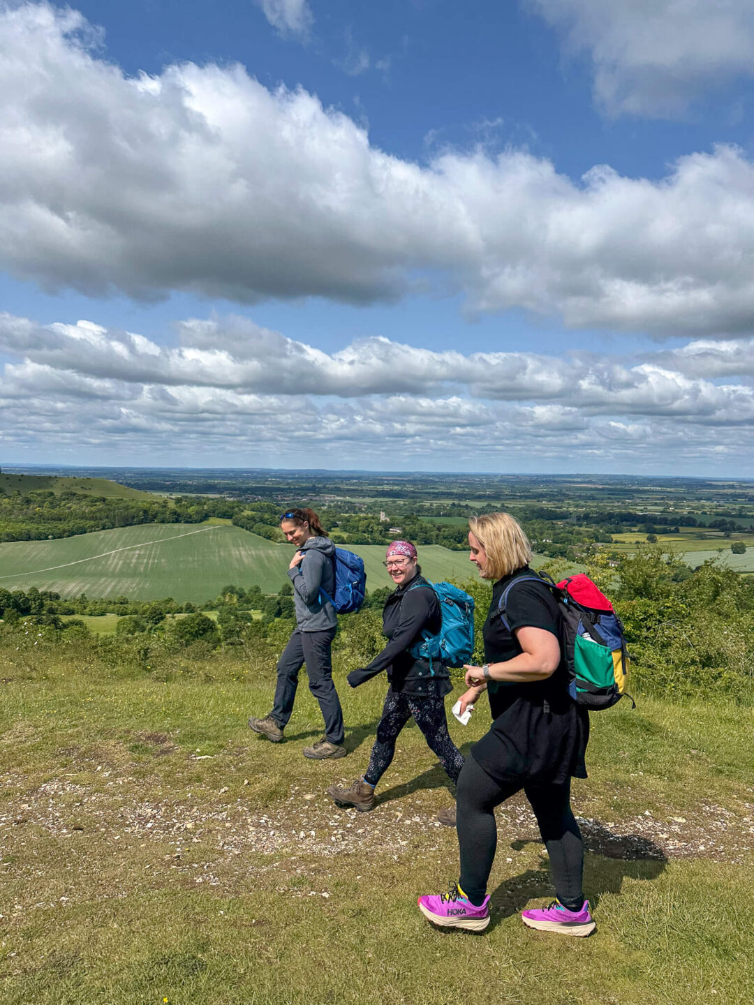 Women hiking on a scenic ridge with backpacks, overlooking countryside in the Chilterns