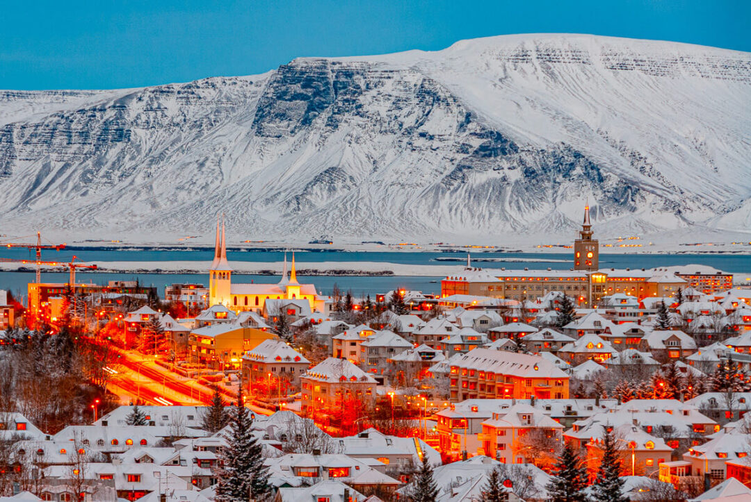 Reykjavik city at dusk with snowy mountain in background