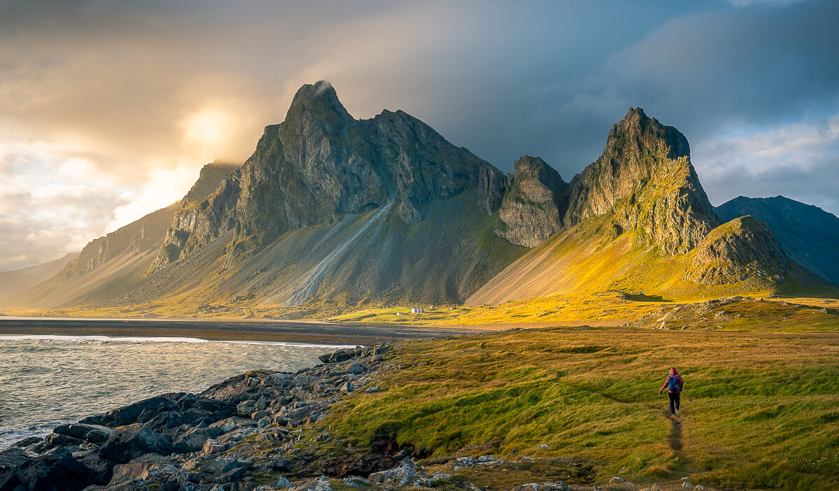 hiker on beach with mountains and cloudy ski in Iceland