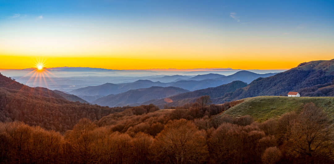 Sunrise over mountain valleys and forests with rolling hills in the distance, Europe landscape view.