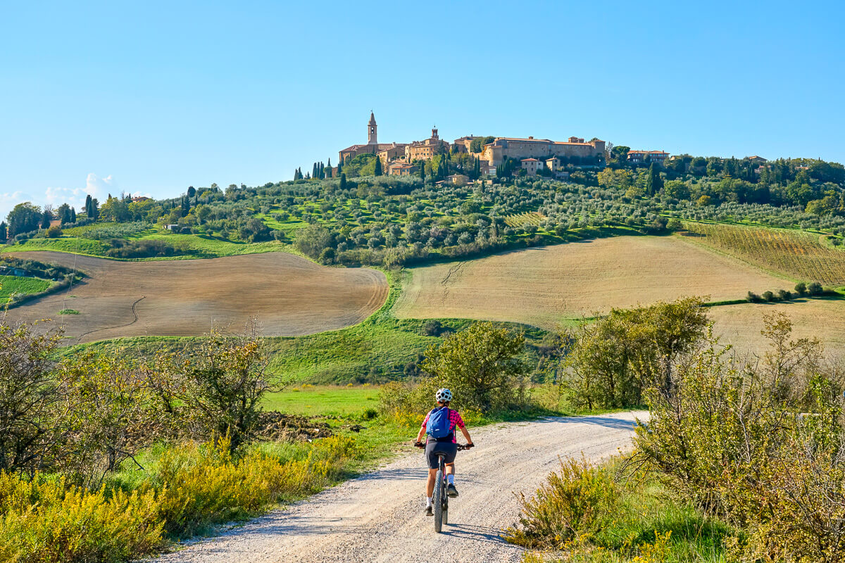Woman cycling along a country road with a hilltop castle in the distance across rolling fields