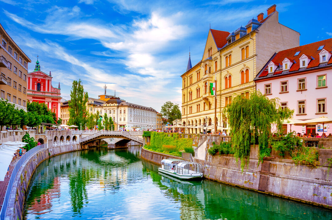 Canal-side bridge and historic buildings along a river in a European city under a blue sky