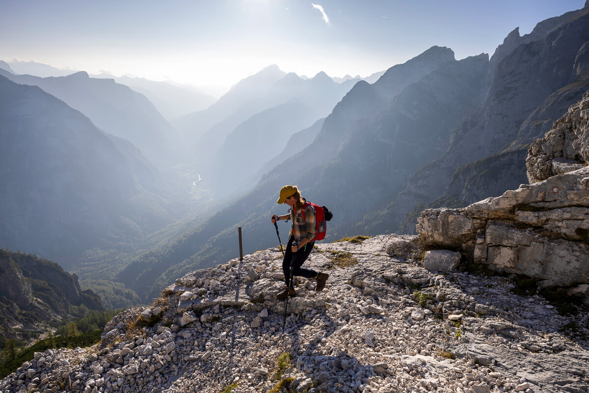 Hiking woman with backpack on a rocky mountain ridge overlooking misty valleys at sunrise