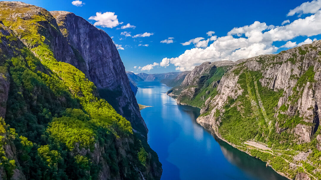 Norwegian fjord with steep cliffs and blue water under a partly cloudy sky
