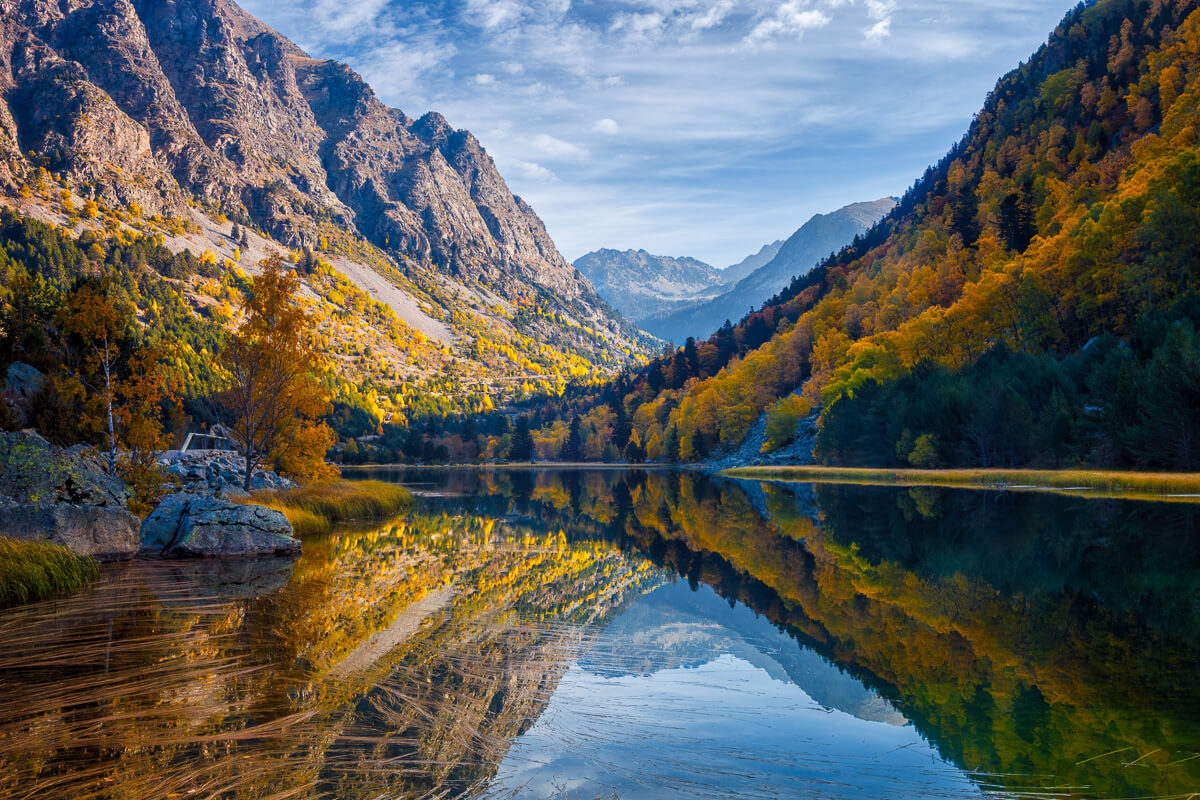 Autumn mountain valley with calm river and mirror reflections, scenic European landscape