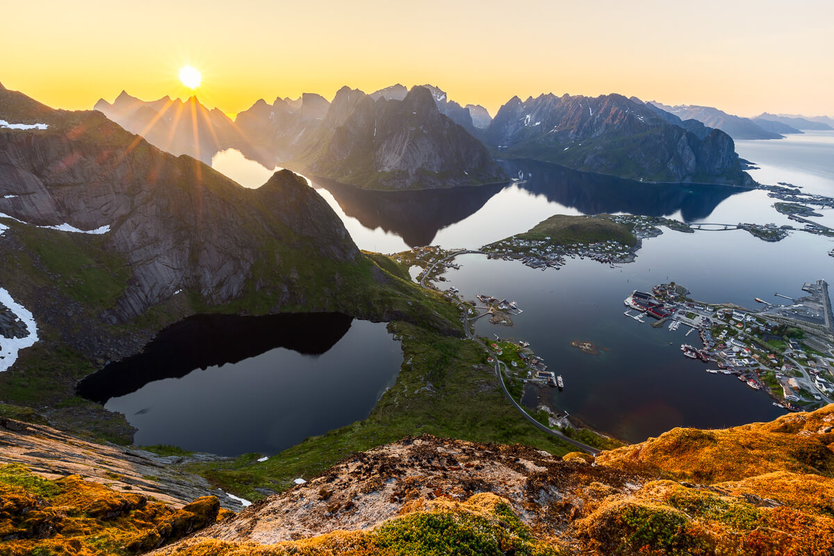 Sunrise view over Norwegian fjords, mountains and coastal village from a hillside viewpoint