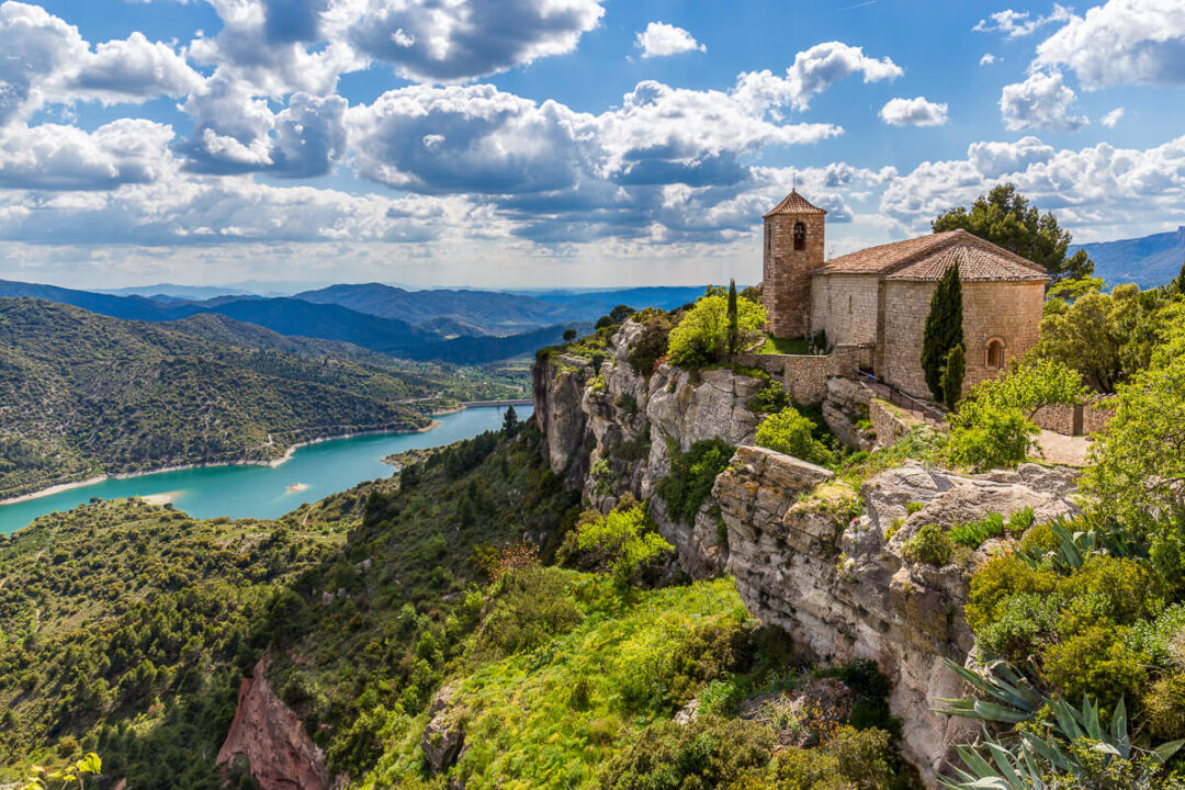Women’s adventure holiday viewpoint over a lake and mountains beside an old stone chapel in Europe