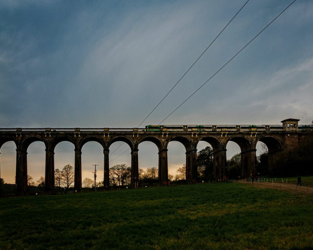 Viaduct on a hiking route near London at sunrise, with arch bridge and green fields along the track