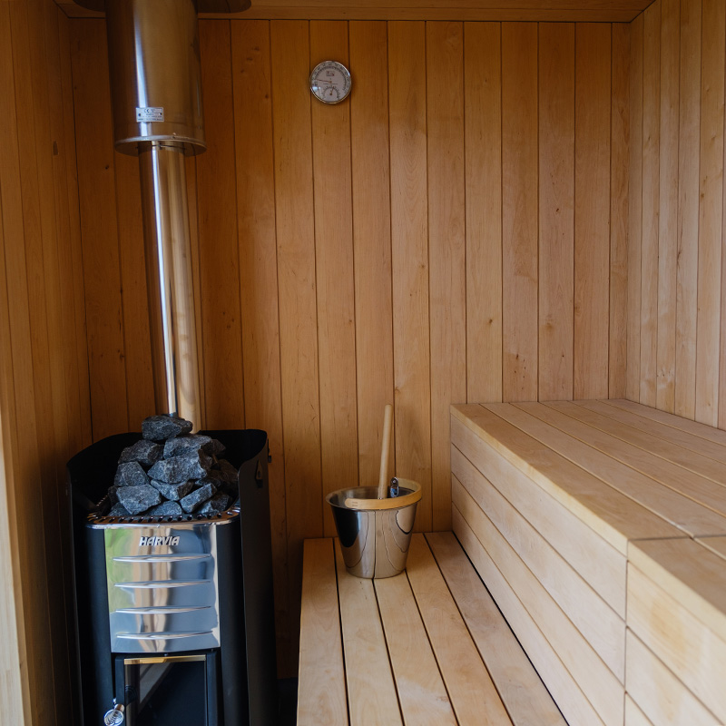 Wooden sauna interior with a steam heater and stone stove, steam room in the UK