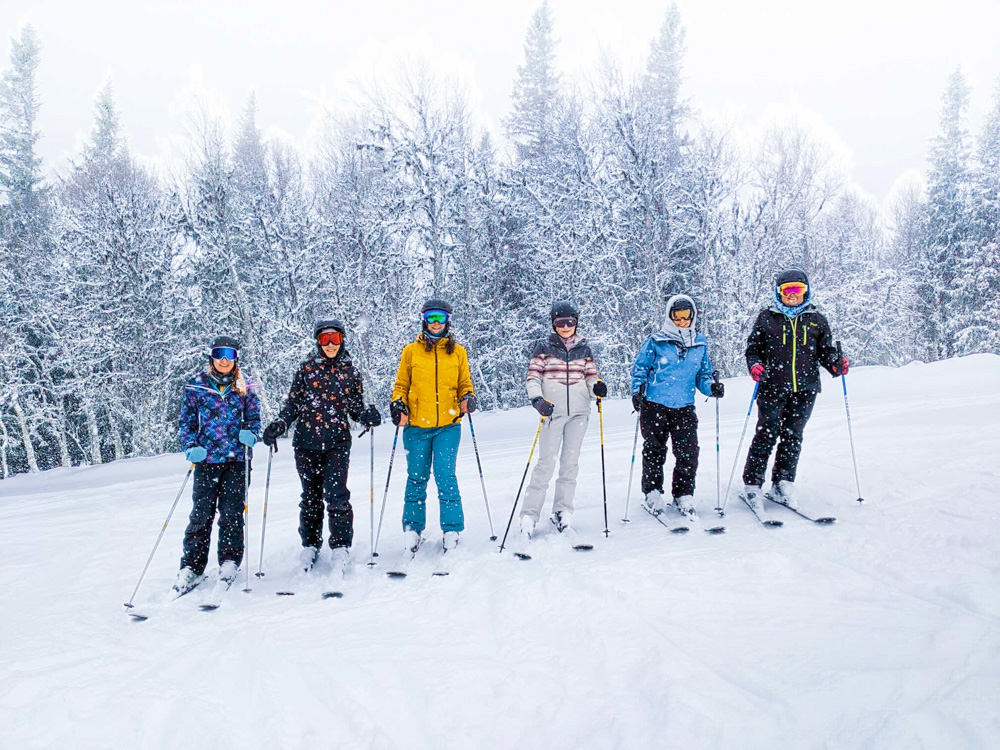 Women trekking with ski poles through snowy woodland in winter, European mountains