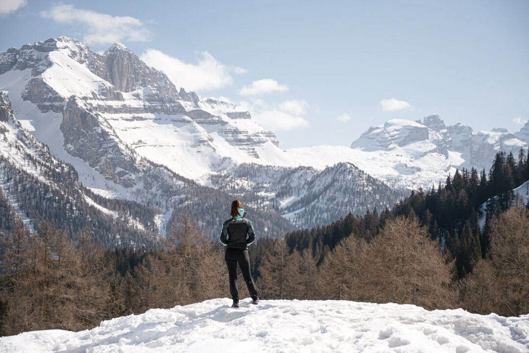 Woman standing on a snow-covered ridge with the Dolomites mountain landscape in the background