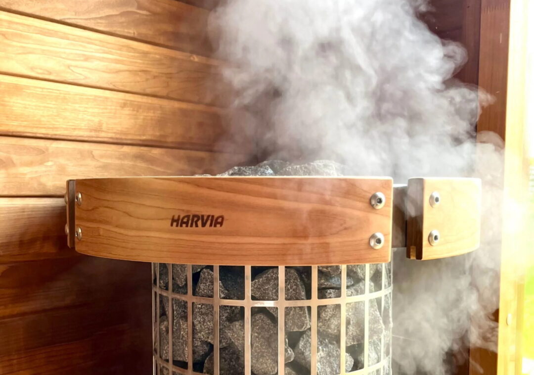 Harvia sauna stove with steam rising inside a wooden sauna room