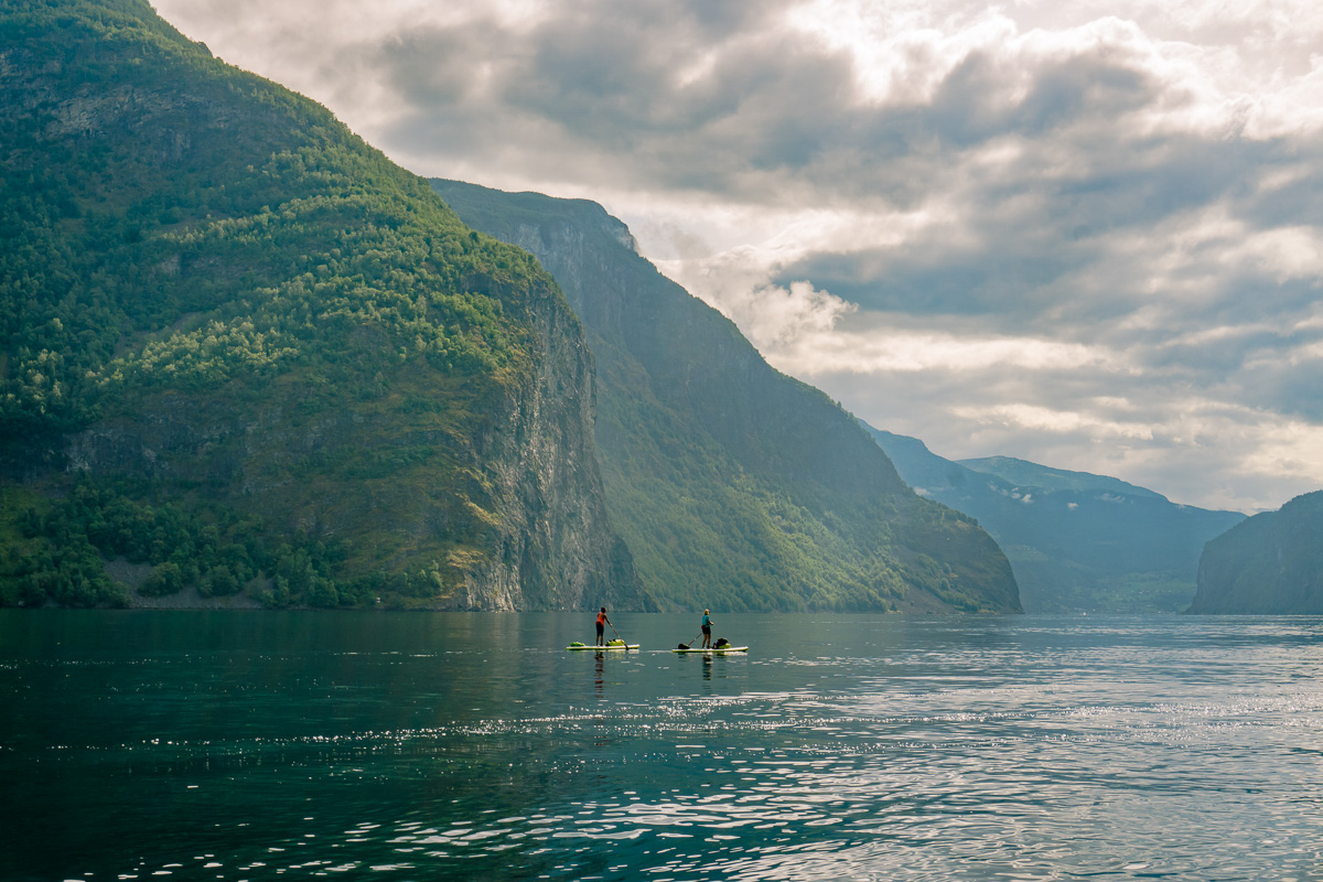 Women kayaking on a calm fjord with steep green mountains in Europe