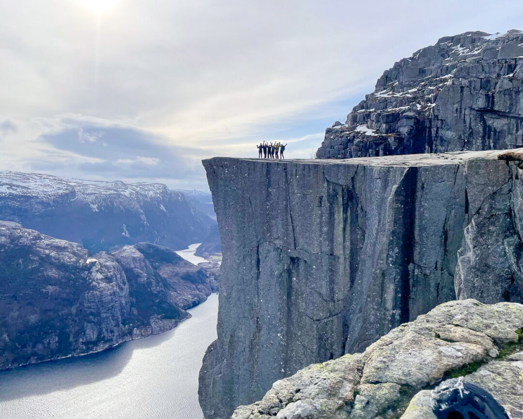 Women hiking along a cliff edge above a fjord in Norway