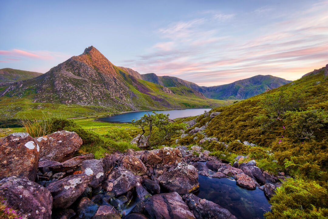 Rocky viewpoint over a mountain lake and green valleys at sunset in Europe