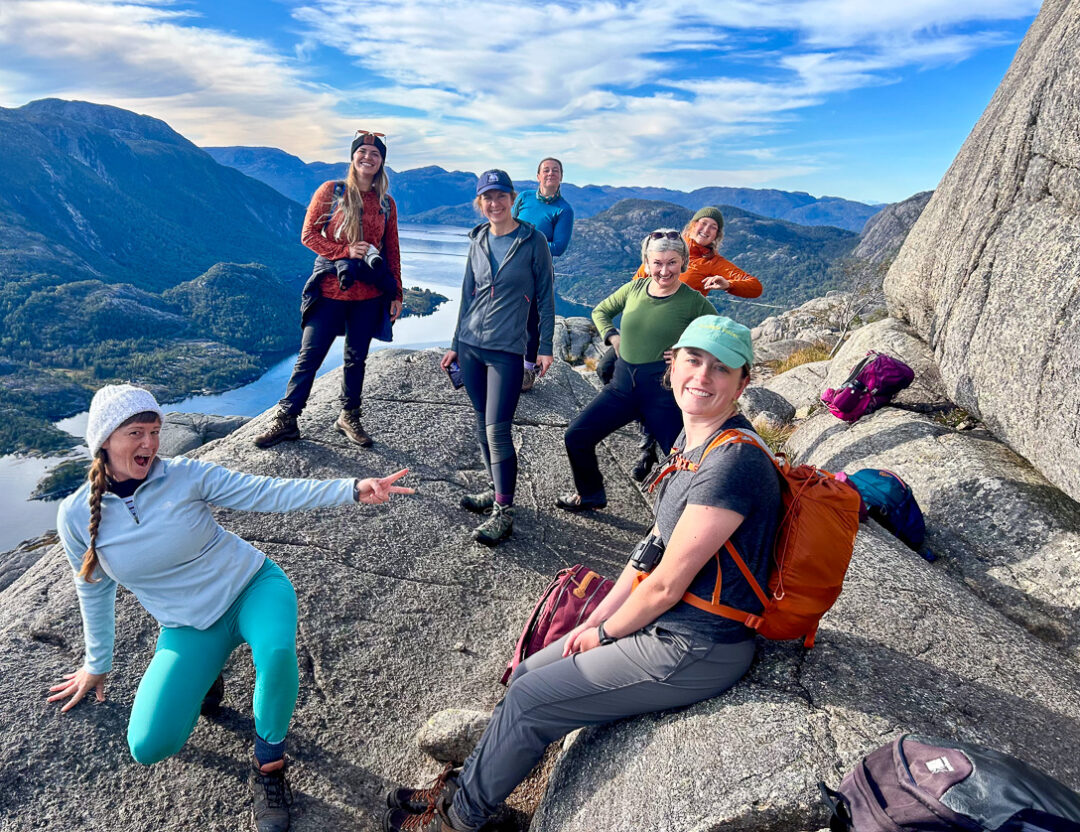 Women hikers with backpacks posing on a mountain ridge overlooking a valley in Europe