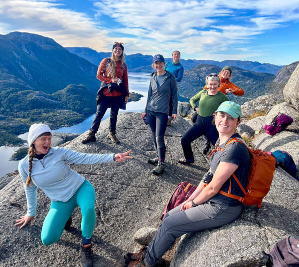 Women hikers with backpacks posing on a mountain ridge overlooking a valley in Europe
