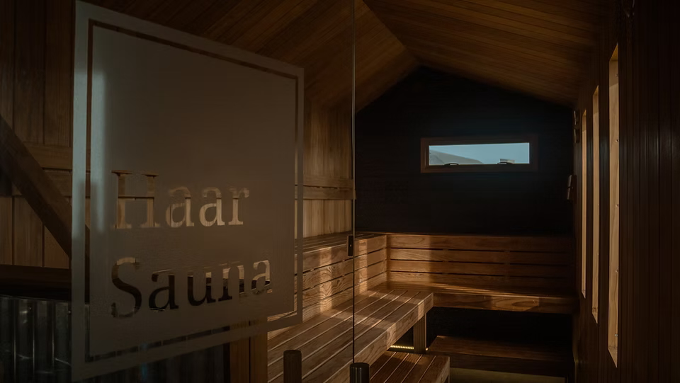 Indoor sauna with wooden benches and signage reading “Sauna”