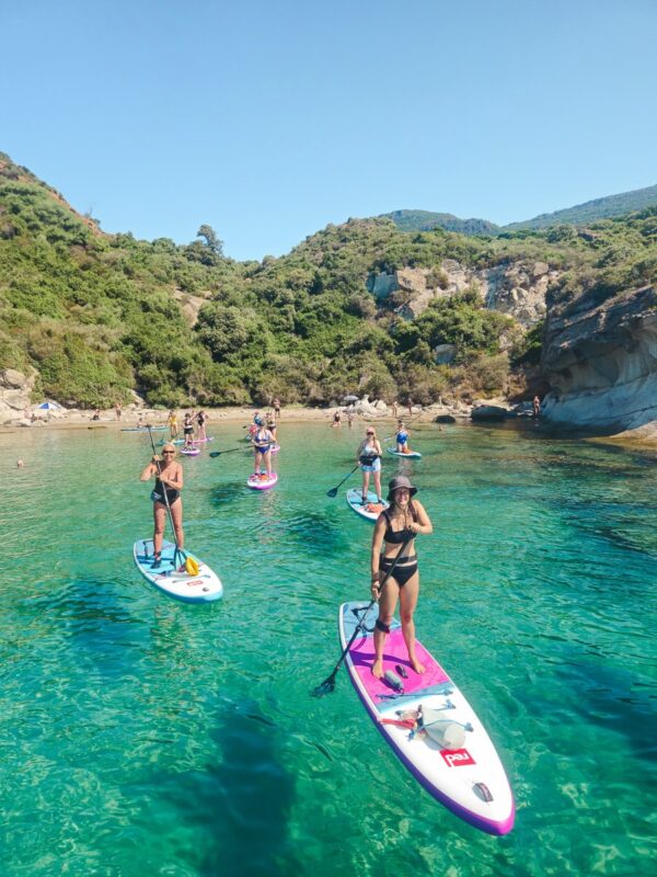 Women paddleboarding at a sheltered cove on Sardinia during a Gutsy Girls adventure holiday