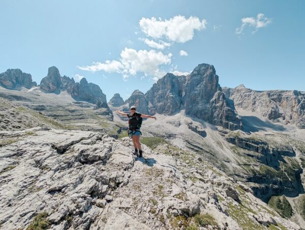 Woman hiking on rocky trail in the Dolomites mountains, Italy, overlooking jagged peaks and valleys