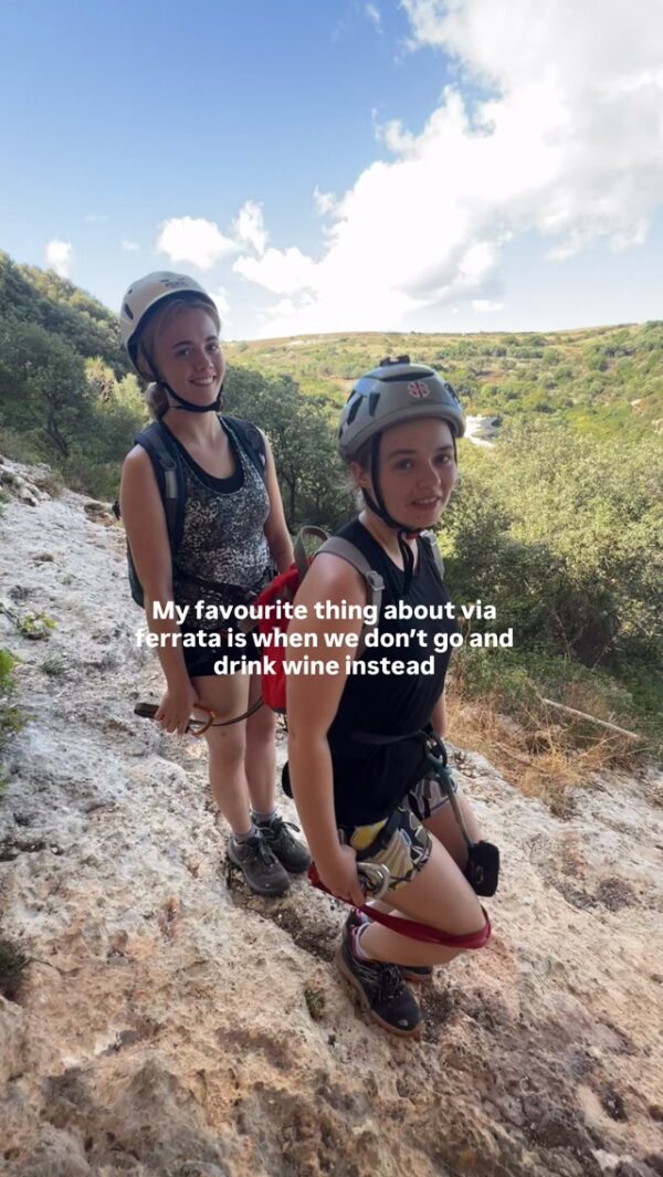 Women on via ferrata on a rocky viewpoint; “don’t go and drink wine instead”