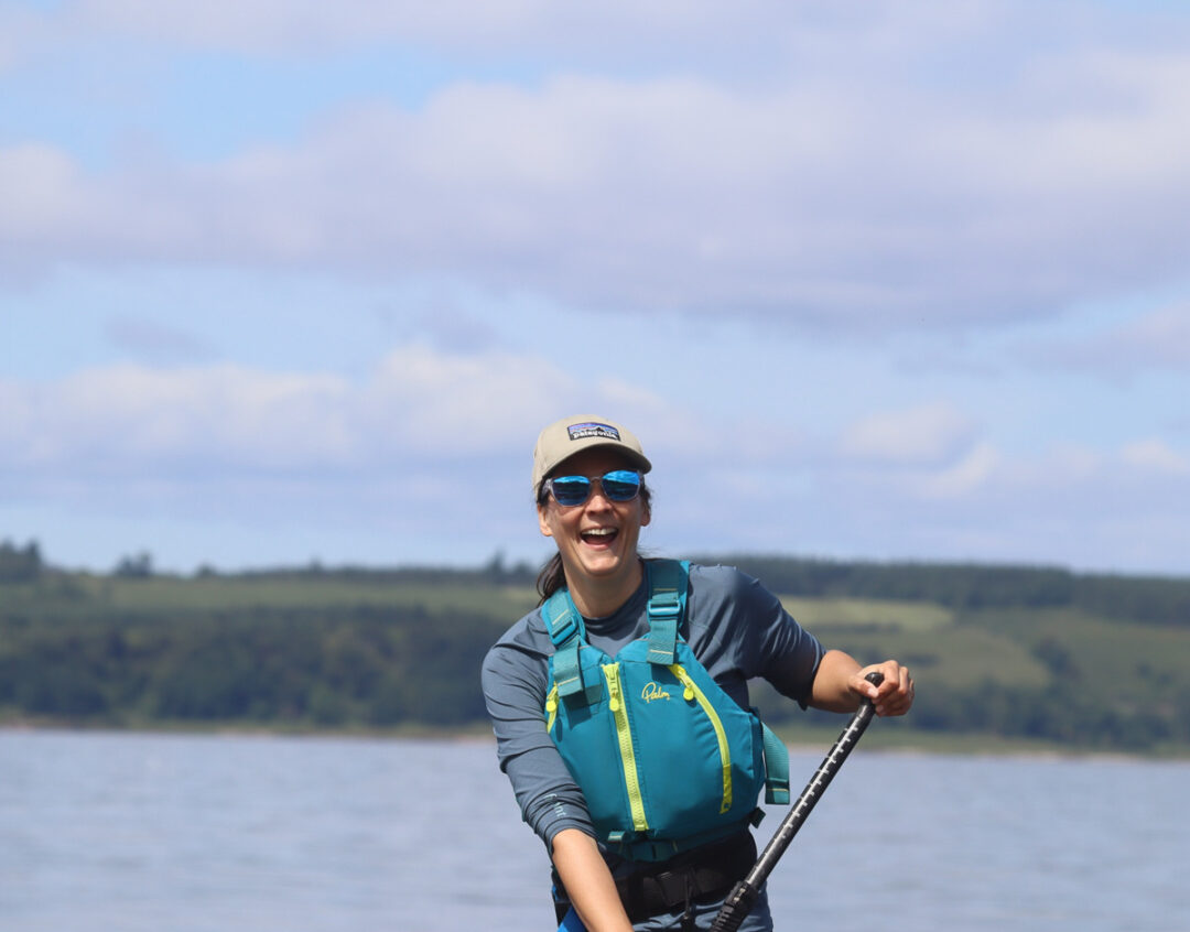 Woman smiling with holding a paddle while being active on the water