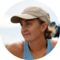 Woman outdoors wearing a cap and blue top, looking off to the side