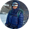 Smiling woman in blue winter jacket and helmet on snowy mountain slopes, winter adventure