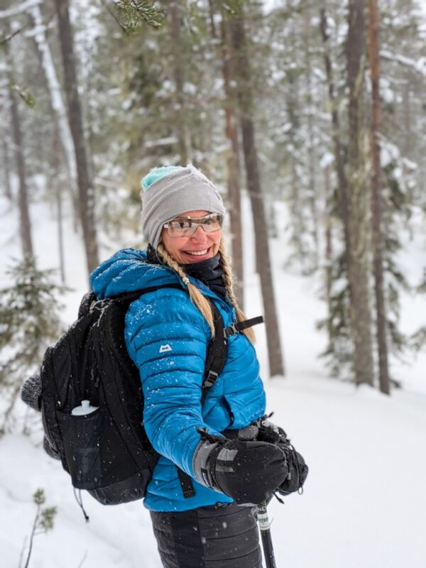 Woman snowshoeing through a snowy forest on a winter adventure holiday.