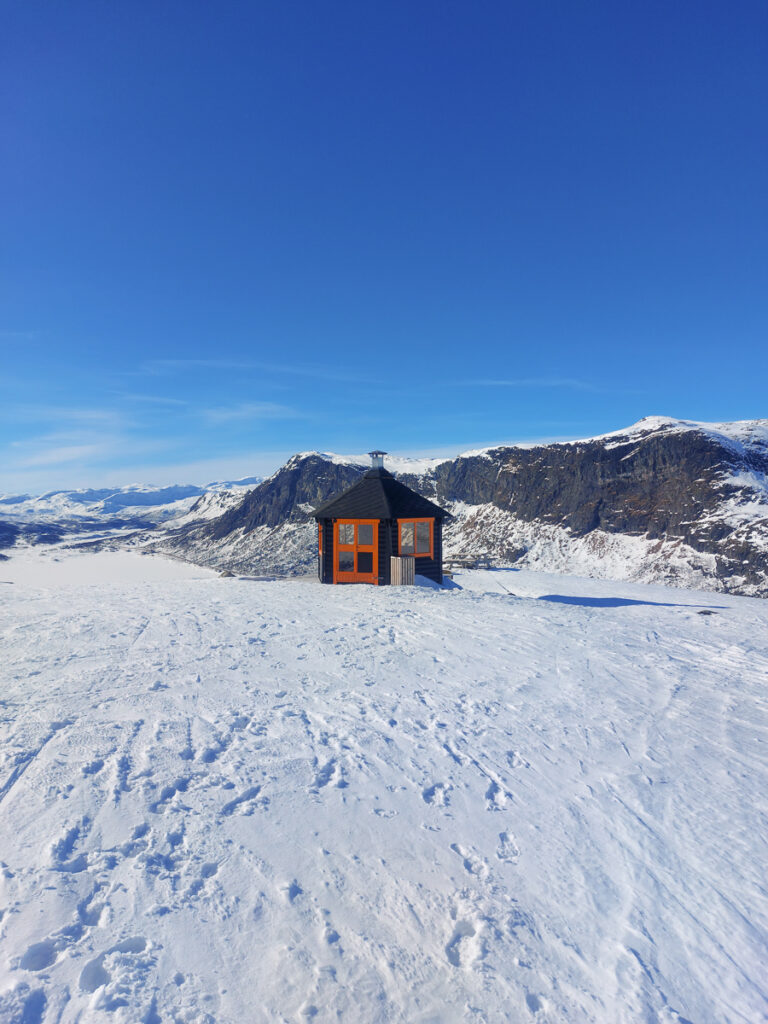 Snowy mountain landscape with a wooden ski cabin in the Alps under a clear blue sky