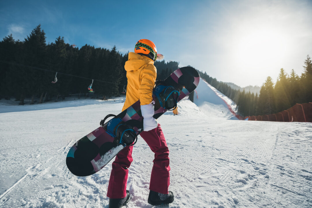 Woman snowboarding on a snowy ski slope, wearing a helmet and goggles in the mountains