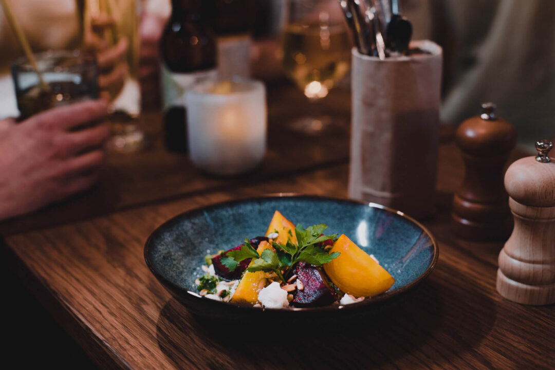 Fresh salad bowl on a restaurant table, with blurred drinks and cutlery in the background