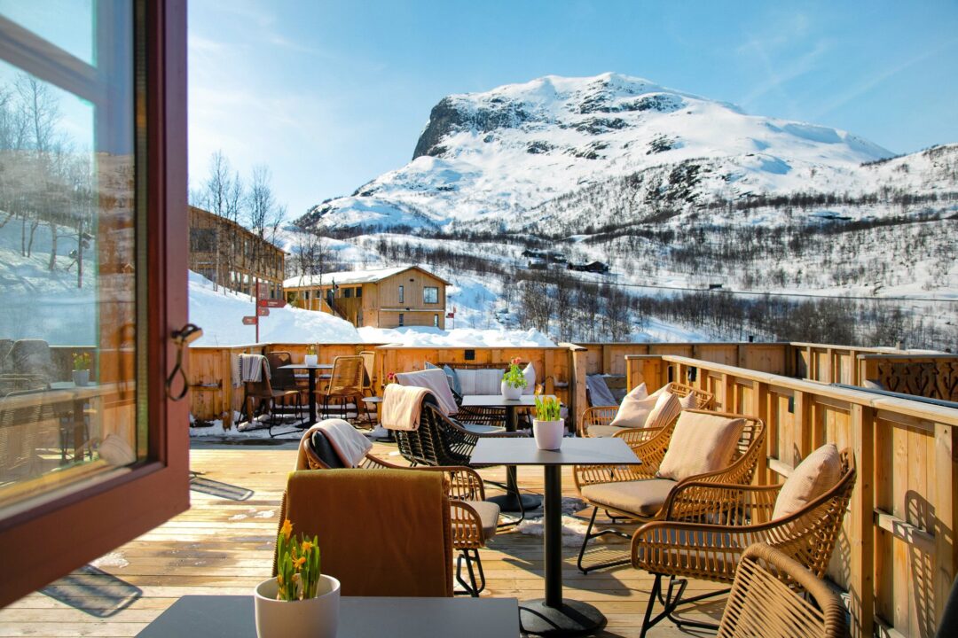 Snowy mountain view from a chalet terrace in Norway, with outdoor seating in the winter landscape