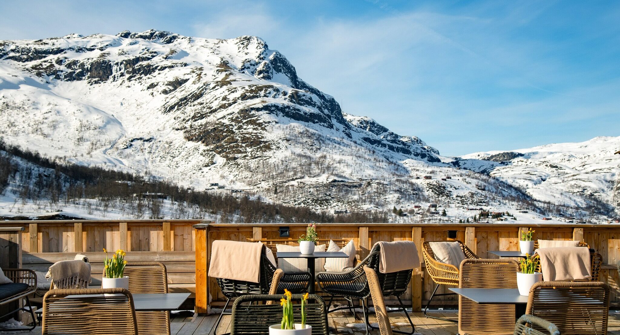 Snowy Norwegian mountain peaks with a sheltered terrace seating area overlooking the ski slopes