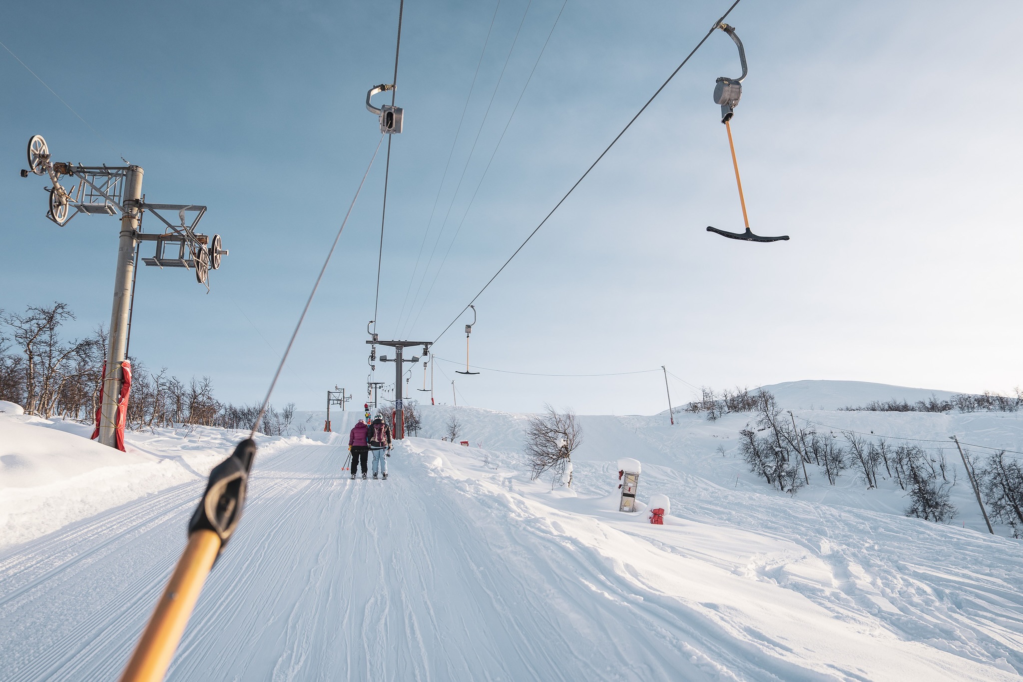 Ski chairlift above a snowy slope with skiers waiting in winter conditions