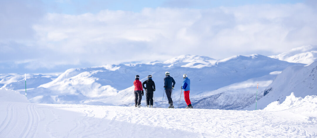Women skiing on a snowy mountain slope with ski poles under a clear blue sky
